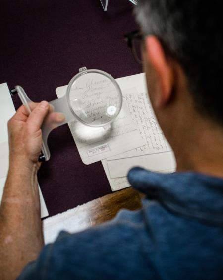 Person using a magnifying glass to read a document